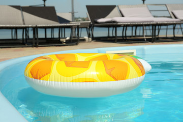 Fototapeta na wymiar Colorful inflatable ring floating in swimming pool on sunny day, outdoors