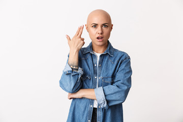 Beautiful displeased bald woman posing isolated over white wall background make gun gesture.