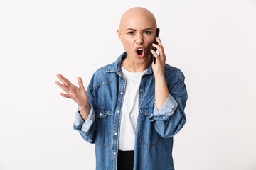 Displeased angry bald woman posing isolated over white wall background talking by mobile phone.