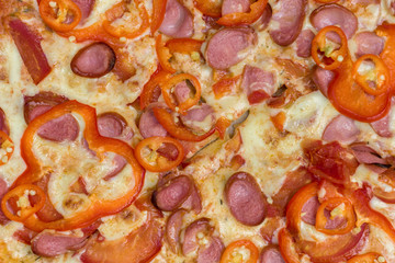 cooked pizza with cheese, sausages and red bell pepper close up. rough texture surface. top view