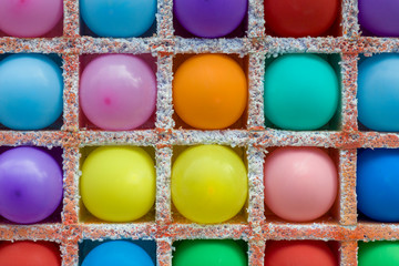 bright multi-colored round balloons in square niches from styrofoam close up in a dash. rough surface texture