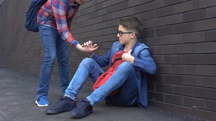 Kind teenage student giving helping hand to bullied nerd boy, supportive friend