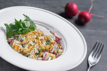 Fresh mixed salad with eggs, salad leaves and other vegetables, served on a plate on a dark background.