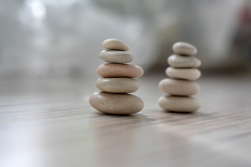 Fototapeta na wymiar Harmony and balance, two cairns, simple poise pebbles on wooden light white gray background, simplicity rock zen sculpture