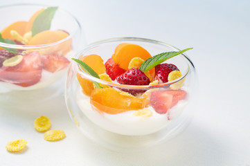 Vitamin dessert of fresh strawberries, apricots and cornflakes with cream on a white background
