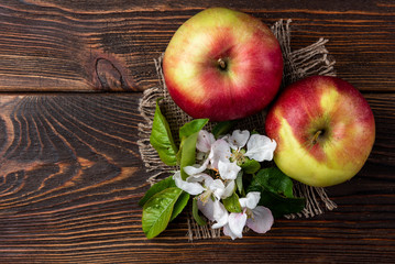 Red apple with flowers on dark wooden background.