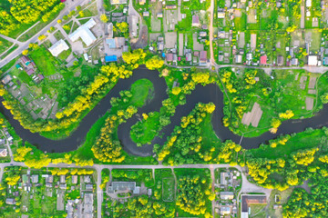 Aerial view landscape of winding small river among the small town, stream in green field.