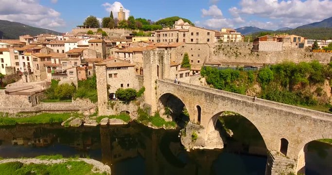Medieval village in Catalonia surrounded by vegetation with ancient bridge and tower