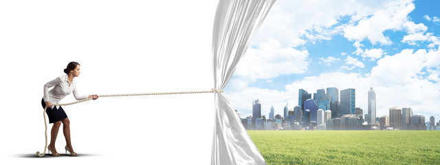 Young woman opening white curtain and presenting modern city landscape