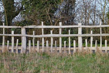 Unusual wooden fence with parallel horizontal rails and vertical posts of different lengths in a pattern