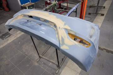 Repair of the rear bumper of a blue car after an accident with the help of multi-colored putty in a...