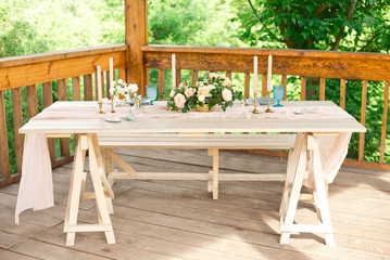 Decorated table for dinner for two person, with plates knife, fork, cheese, wine, wine glasses and flowers in a copper vase.