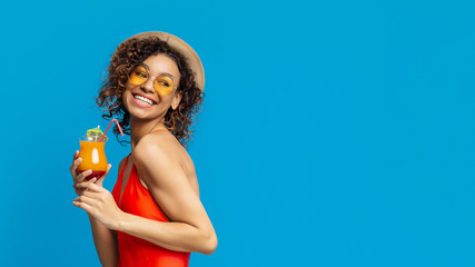 Smiling black girl enjoying summer cocktail and looking at empty space