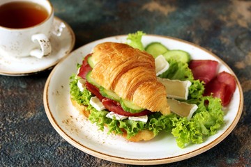 croissant sandwich and tea. breakfast in French. jerky, camembert ch