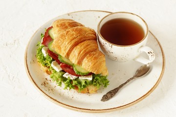 croissant sandwich and tea. breakfast in French. jerky, camembert ch