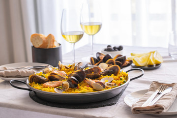 Seafood Paella with  prawns, clams, mussels on saffron rice and vegetables and  bottle of white...