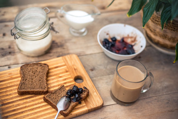 Rustic still life. Cozy summer morning, Breakfast in the fresh air. Homemade food on a wooden table jam, bread, milk, coffee, sugar, flower in brown tones top view