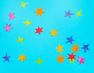 multicolored stars cut from papers on blue paper