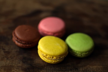 Multi-colored macaroons on a wooden tray. Pink, yellow and green macaroon.