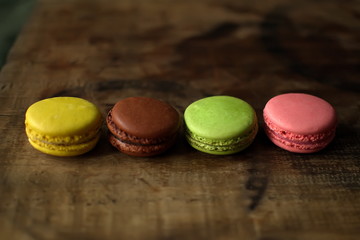Multi-colored macaroons on a wooden tray. Pink, yellow and green macaroon.
