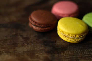 Multi-colored macaroons on a wooden tray. Pink, yellow and green macaroon.