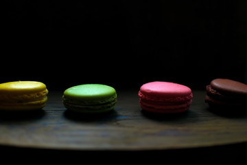 Obraz na płótnie Canvas Multi-colored macaroons on a wooden tray. Pink, yellow and green macaroon.