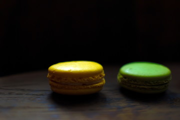 Multi-colored macaroons on a wooden tray. Pink, yellow and green macaroon.