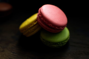 Multi-colored macaroons on a wooden tray. Pink, yellow and green macaroon.