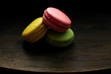 Multi-colored macaroons on a wooden tray. Pink, yellow and green macaroon.