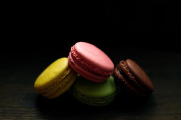 Multi-colored macaroons on a wooden tray. Pink, yellow and green macaroon.