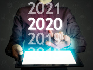 Naklejka na ściany i meble Woman select 2020 on his tablet pc. New 2020 year in high tech.