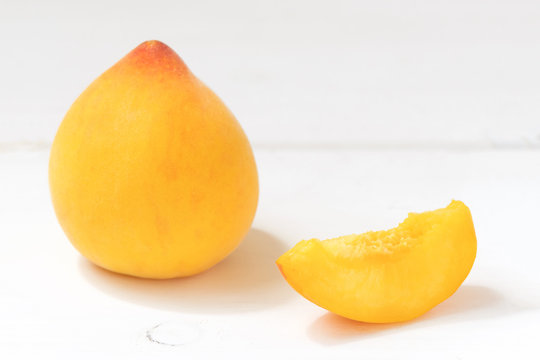 Yellow italian fresh peach percoche on the white wooden background with copy space, minimal concept, selective focus
