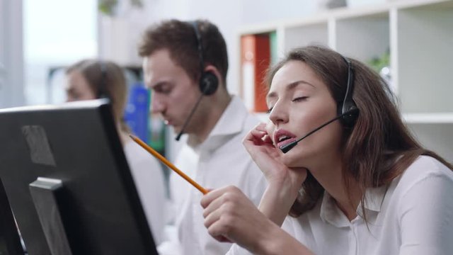 Close up young woman service operator taking calls in busy call center office feel sad bored business background workers computer corporate headset job man service group finance phone slow motion