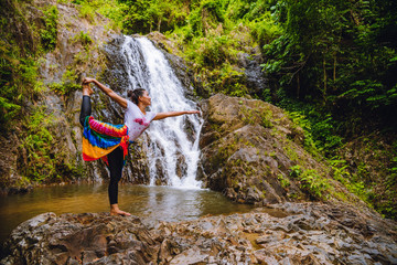 Asian women relax in the holiday. Play if yoga.  Play if yoga at waterfall On the Moutain. exercise, good health, travel nature, Travel relax. Travel Thailand. ( Huai Toh waterfall )