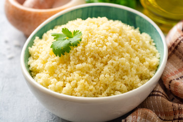 Cooked couscous with cilantro in ceramic bowl on concrete background. Selective focus. - obrazy, fototapety, plakaty