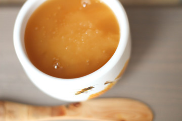 White bowl of honey. Wood table. Rustic style