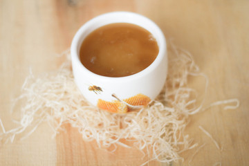 White bowl of honey. Wood table. Rustic style