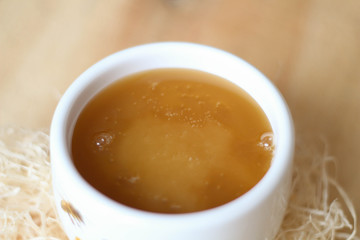 White bowl of honey. Wood table. Rustic style