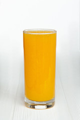 large thin transparent glass filled with cold summer drink freshly prepared juice is photographed on a white wooden table isolated background picture for the menu
