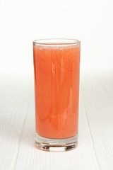 large thin transparent glass filled with cold summer drink freshly prepared juice is photographed on a white wooden table isolated background picture for the menu