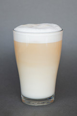 large transparent glass filled with cold summer drink coffee with milk photographed on the isolated gray background picture for the menu