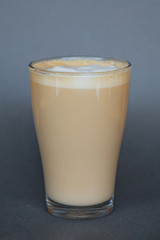 large transparent glass filled with cold summer drink coffee with milk photographed on the isolated gray background picture for the menu