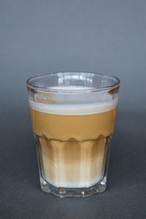 large transparent glass filled with cold summer drink coffee with milk photographed on the isolated gray background picture for the menu