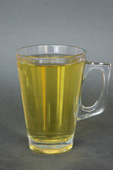 a transparent mug with a handle filled with hot bright tea of intense color on a dark gray background, the photo is suitable for the menu of cold tea in the cafe
