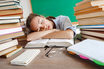 Tired student lies and sleep on the books. Photo of young girl in school. Back to school!