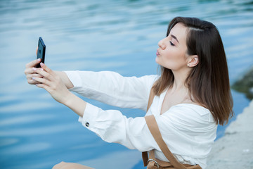 Girl outdoors texting on her mobile phone. Girl with phone. Portrait of a happy woman text sms message on her phone.