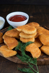 Chicken nuggets with greens and sauce on a wooden Board. Fast food, snack, dinner in European style.