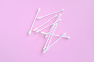 Group of white personal cotton swab with selective focus on pink neutral background with empty space for text. White hygienic cotton buds for daily routine. Soft cotton ear sticks. Health care tools 