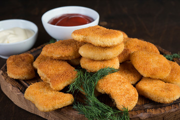 Chicken nuggets with greens and sauce on a wooden Board. Fast food, snack, dinner in European style.