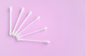 Group of white personal cotton swab with selective focus on pink neutral background with empty space for text. White hygienic cotton buds for daily routine. Soft cotton ear sticks. Health care tools 